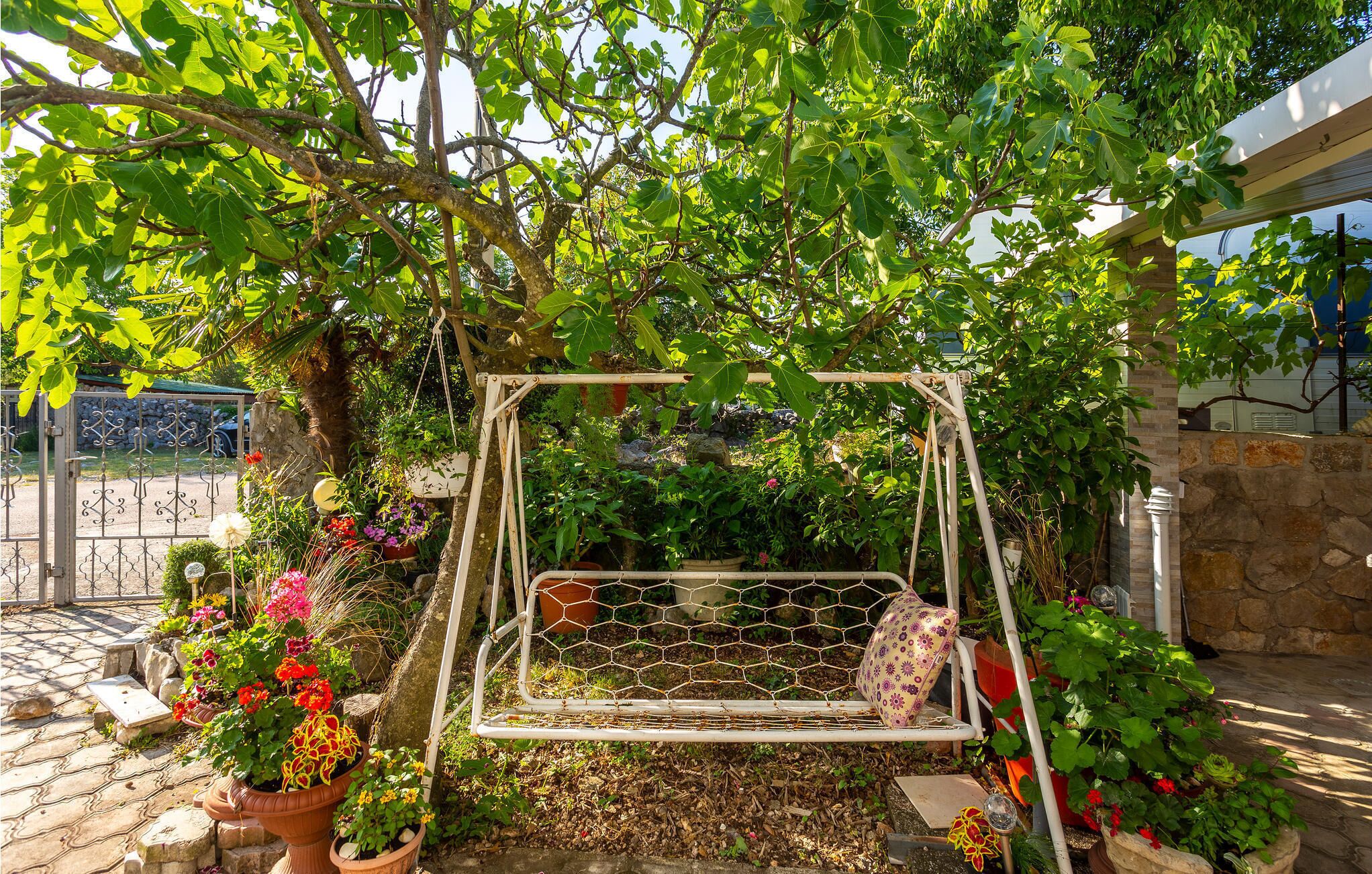 A garden with a swing set, potted plants, and a stone wall.