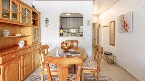 A dining area with a wooden table and chairs, a kitchen visible through an archway, and a mirror on the wall. - Cozy apartment in La Mata, Torrevieja (La Mata, Torrevieja)