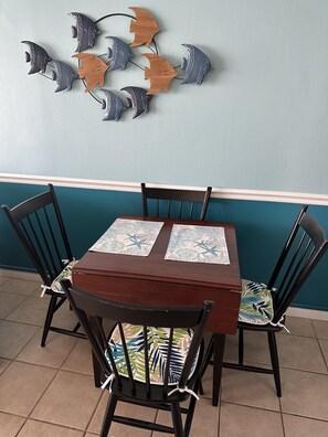 A dining area with a wooden table and chairs, a wall-mounted fish decoration, and a teal accent wall.