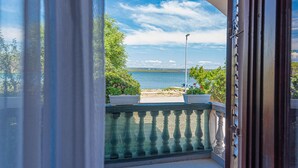 A view from a balcony overlooking a body of water, with a clear sky and some greenery. - Awesome apartment in Raslina (Raslina)