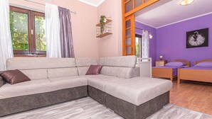 A modern living room with a sectional sofa, a wooden bed, and a purple accent wall. - Awesome apartment in Raslina (Raslina)