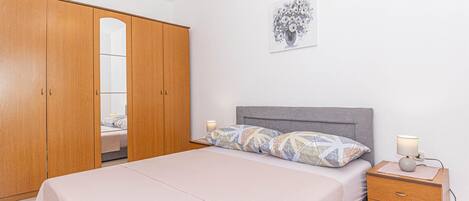 A bedroom with a bed, bedside tables, a wardrobe, and a wall-mounted artwork.