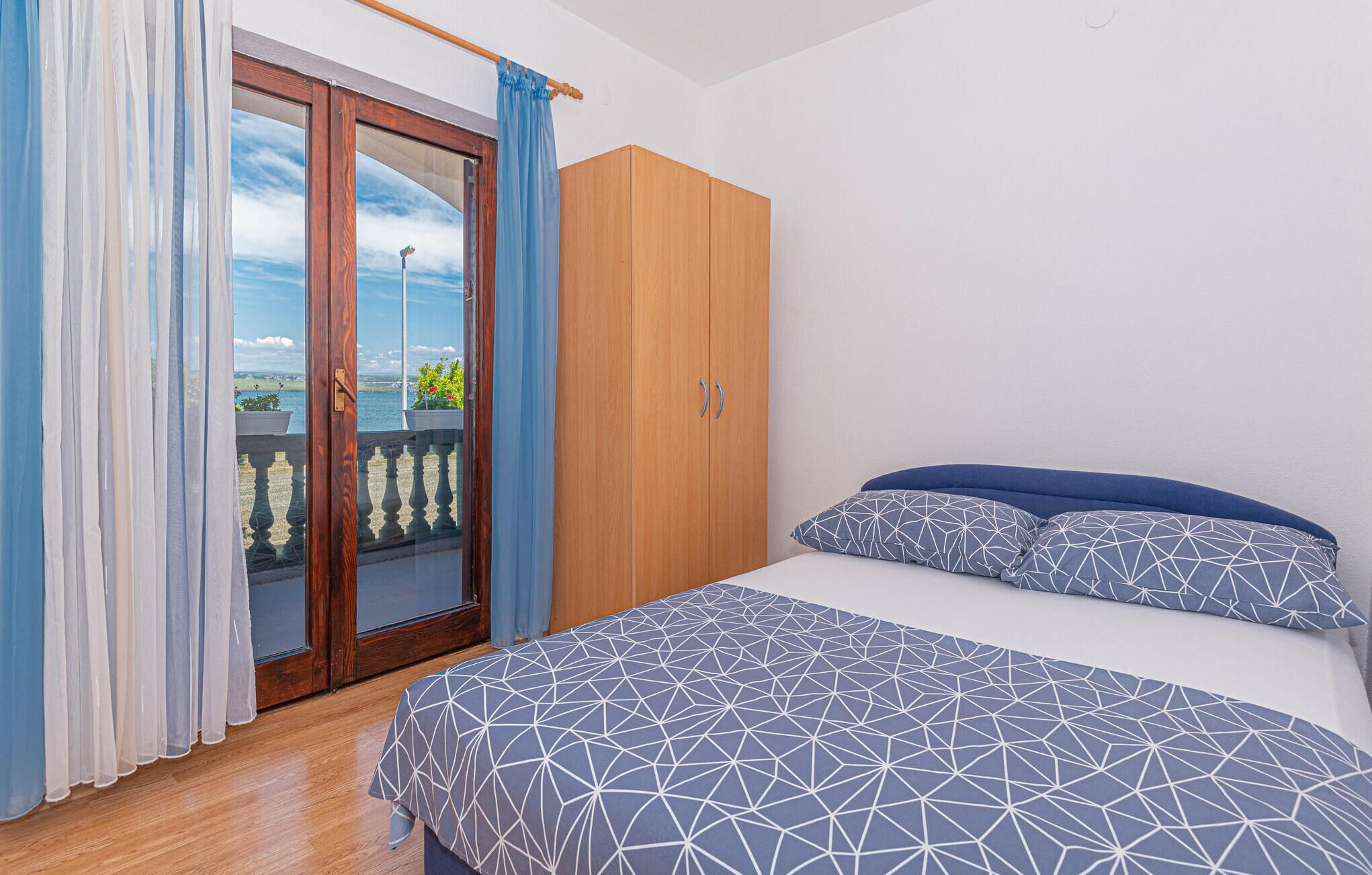 A bedroom with a bed, a wardrobe, and a view of the sea through a glass door.