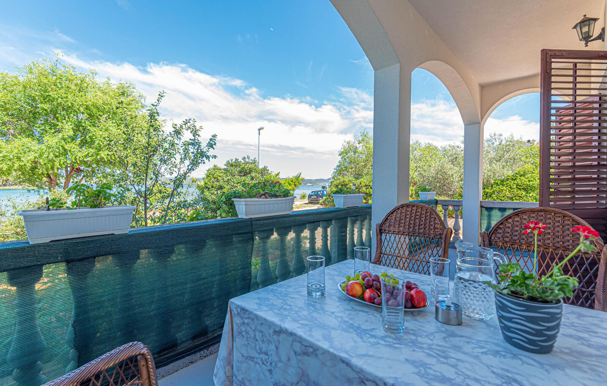 A terrace with a marble table, wicker chairs, and potted plants.