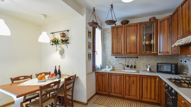 Een keuken met houten kastjes, een gasfornuis, een magnetron en een spoelbak.