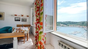 A room with a dining table set for two, a window with a view of a harbor, and a radiator near the window. - Amazing apartment in Portovenere (Portovenere)