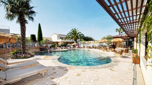 Un espace piscine comprenant des chaises longues, un jacuzzi et une pergola.