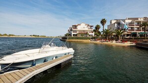 Un bateau était amarré dans une marina, et en arrière-plan, on pouvait voir un bâtiment doté de balcons et bordé de palmiers.