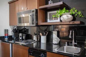 Una cocina moderna con microondas integrado, estufa y pileta de acero inoxidable.