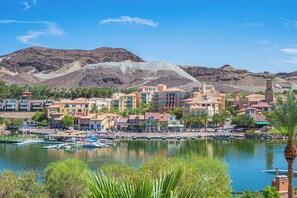A coastal town with buildings, a marina, and mountains in the background.