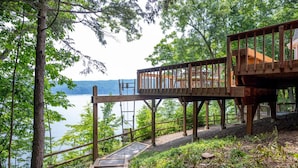 Une terrasse en bois avec un escalier menant à une plateforme d’observation surplombant un lac.