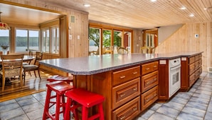 Une cuisine spacieuse dotée d’un grand îlot central, de meubles en bois et offrant une vue sur l’extérieur.
