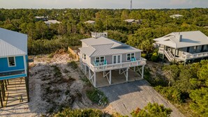 Une maison située sur la côte, dotée d’un balcon et entourée d’une végétation luxuriante ainsi que d’autres maisons.