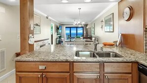 A kitchen with granite countertops, wooden cabinets, and a built-in sink. - Gulf Front Beach Life (Fort Myers Beach)