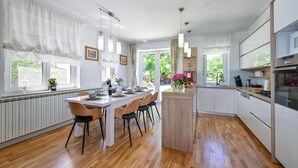Une cuisine moderne dotée d’un îlot central, d’un plancher en bois et offrant une vue sur le jardin.