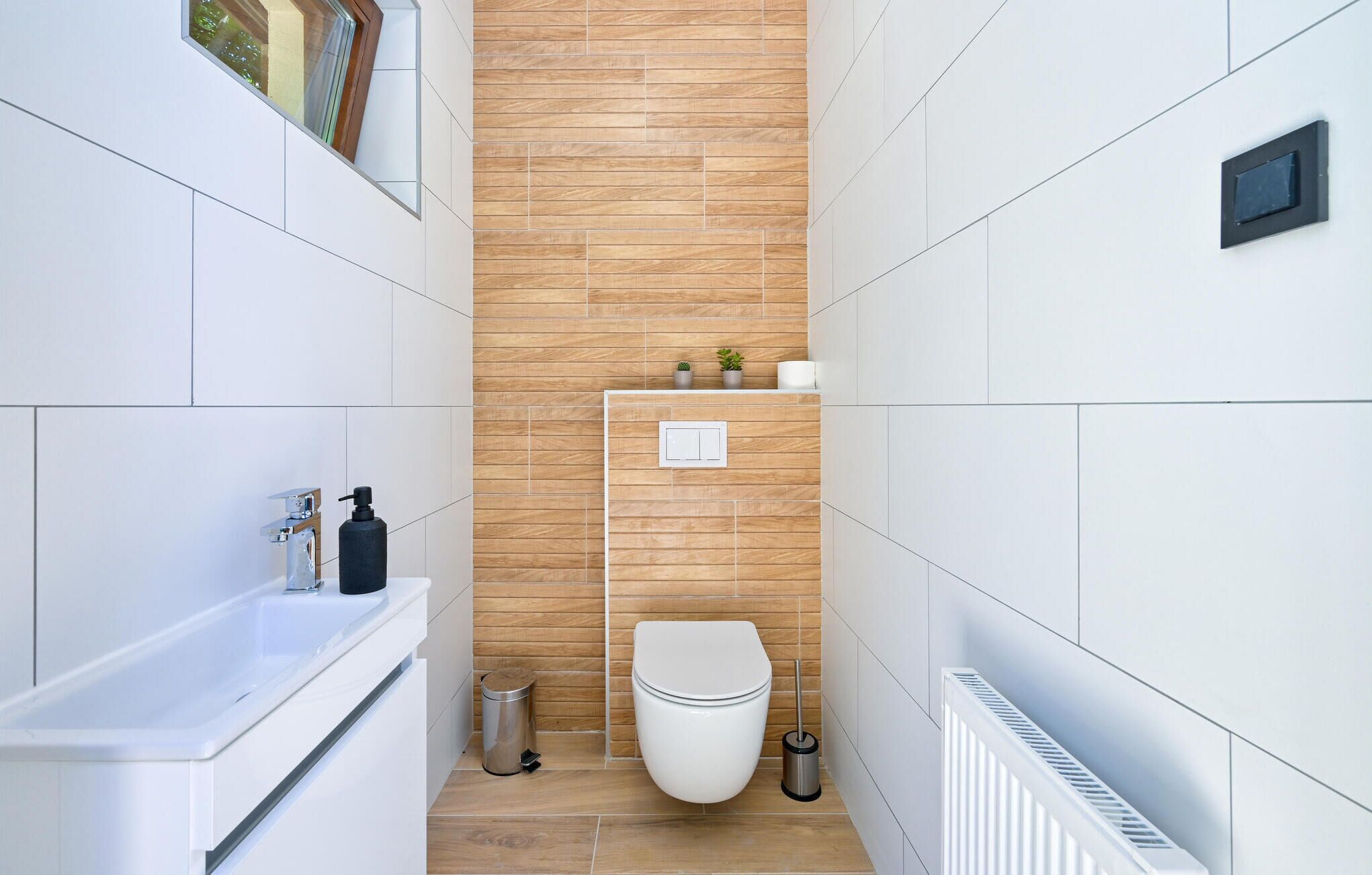 Un baño moderno con una bañera blanca, un inodoro y un radiador.