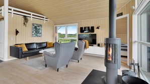Un salon moderne avec une cheminée, des murs en bois, un canapé et un téléviseur.