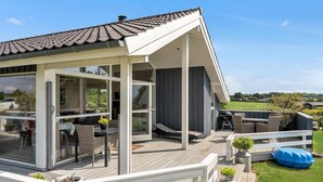 Une maison moderne dotée d’un patio couvert, de portes vitrées et de mobilier d’extérieur.