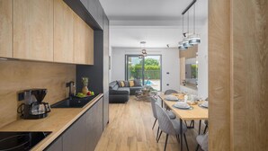A modern kitchen with a coffee maker, a dining area with a table set for two, and a view of the outdoors. - Stunning apartment in Radmani (Radmani)