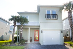 A two-story house with a red door, a balcony, and a garage.