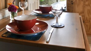 Ein Holztisch mit roten und blauen Tellern, einem Weinglas und einem Smartphone.