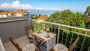 Ein Balkon mit Tisch und Platz für zwei Personen, zwei Stühlen und einem schönen Blick auf Stadt und Meer.