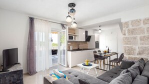 A modern living room with a grey sofa, a TV stand, and a dining area with a table and chairs. - 3 bedroom cozy home in Povlja (Povlja)