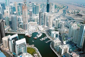 A high-rise urban area with a marina, featuring modern buildings, a complex road network, and a body of water with boats.