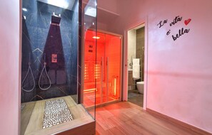 Un baño moderno con cabina de ducha de vidrio, suelo de madera y una pared con una frase motivacional.