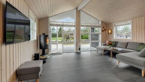 Un salon moderne avec une cheminée, un canapé, une table basse et un téléviseur fixé au mur.