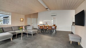 A modern living room with a grey sofa, a round coffee table, and a dining area with a table set for four. - Nice home in Tarm with sauna (Tarm)