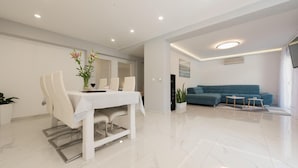 Uma sala de estar moderna com área de jantar, apresentando um sofá, uma mesa de jantar com cadeiras e uma planta em vaso.