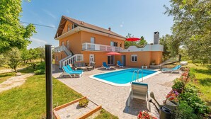Uma casa de dois andares com piscina, área de estar externa e jardim.