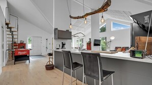 Une cuisine moderne avec un îlot central, des tabourets de bar et une échelle en bois.