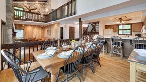 Une salle à manger spacieuse avec un plafond haut, des murs en pierre et un plancher en bois.