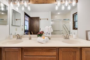 Une salle de bain moderne avec deux lavabos, un grand miroir et un espace douche.