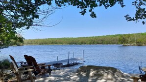 Un cadre idyllique au bord du lac, avec un quai, des chaises en bois et un barbecue.