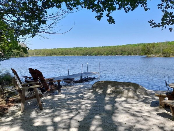 Un cadre idyllique au bord du lac, avec un quai, des chaises en bois et un barbecue.