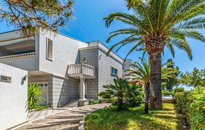 A modern two-story building with a balcony, surrounded by palm trees and a well-maintained garden. - Stunning home in Okrug Gornji (Okrug Gornji)