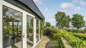 A modern house with large glass doors leading to a wooden deck. - Stunning home in Roslev with kitchen (Roslev)