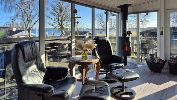 A modern outdoor seating area with two leather chairs and a small round table with a vase of dried flowers. - Stunning home in Roslev with kitchen (Roslev)