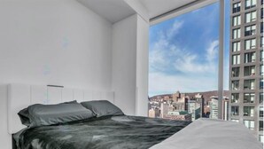Une chambre moderne avec vue sur la ville, un grand lit et un design minimaliste.