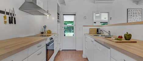 Eine moderne Küche mit weißen Schränken, Holz Arbeitsplatten und einer zentralen Kochinsel.