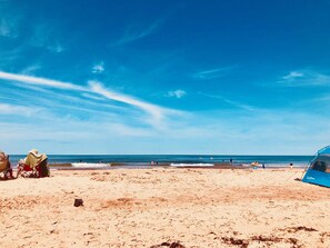 Une plage avec une tente sur laquelle on peut lire l’inscription « LL Bean », et quelques personnes au loin.