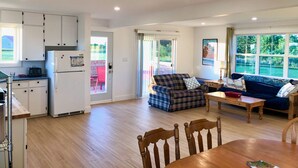 A spacious living area with a kitchen, a dining table, and a sofa. - Renovated family cottage; walk to amazing beach, short drive to golf & town (Sea View)