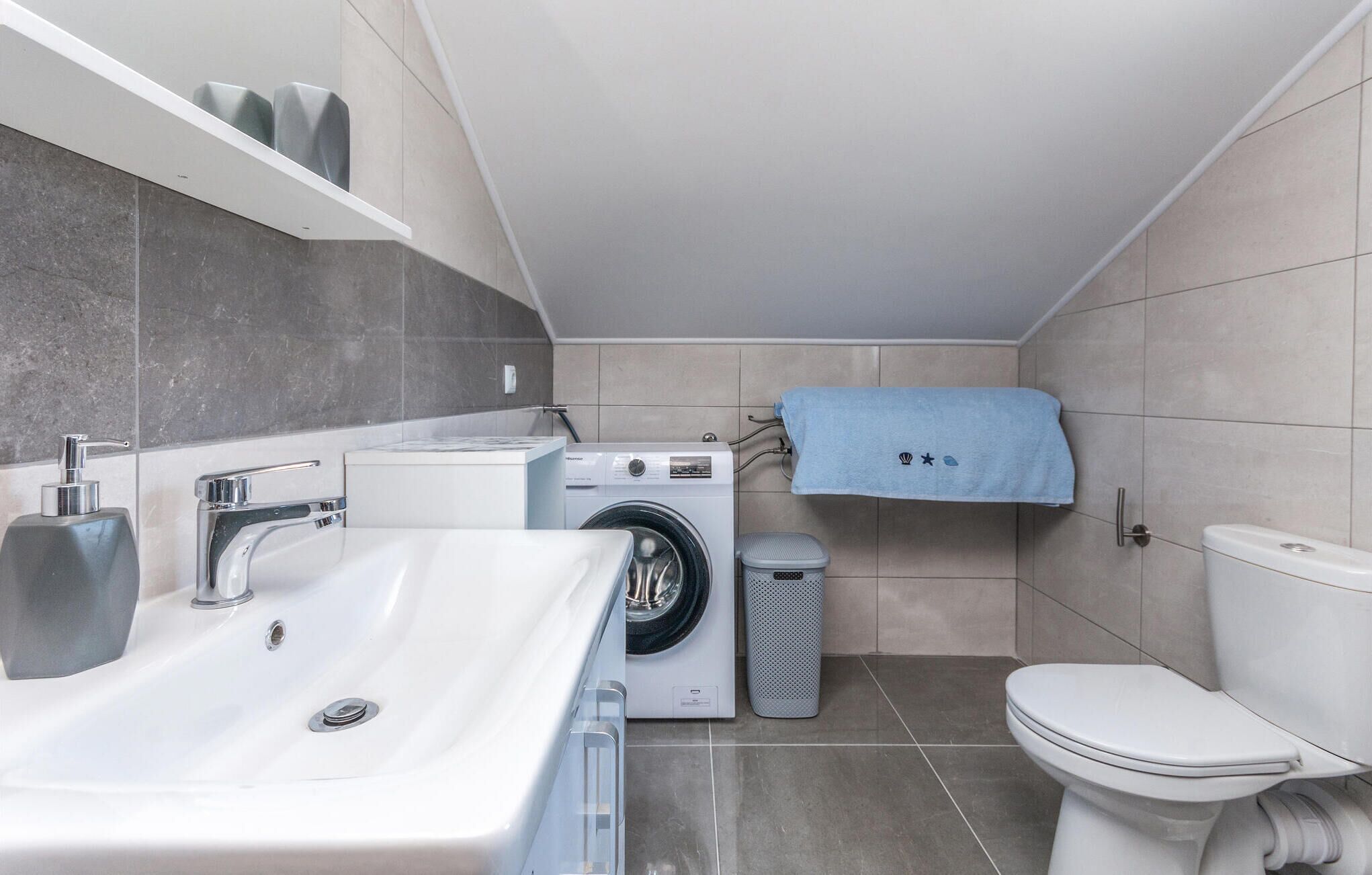 A compact bathroom with a sink, washing machine, and toilet.