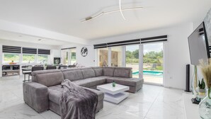 Ein modernes Wohnzimmer mit einer großen Eckcouch, einem Couchtisch und einem Fernseher.