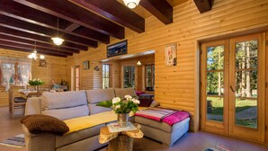 Ein gemütliches Blockhaus-Interieur mit einer Couch, einem Couchtisch und einem Essbereich.