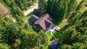 Eine Vogelperspektive eines Hauses, umgeben von dichtem Wald, mit auffälligem Auffahrtsweg und kleiner Terrasse.