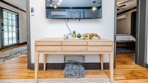 Habitació moderna amb escriptori de fusta, televisió penjada, una petita planta i una figura d'animal daurada decorativa.